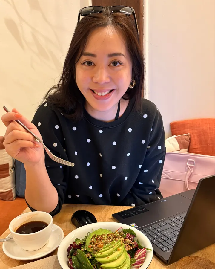 Essen working on her laptop in a cafe with a coffee and a salad